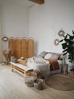 Braune Holztür neben braunem geflochtenem Sessel im Hygge-Schlafzimmer