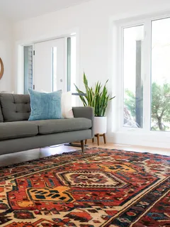Stylisches Interieur mit türkisfarbenem 2-Sitzer Sofa und rotem Teppich