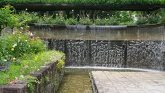 Wasserfall im Garten mit Blumen und frischem Grün