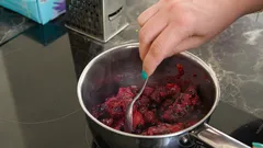 Person rührt einen Topf mit Essen auf dem Herd