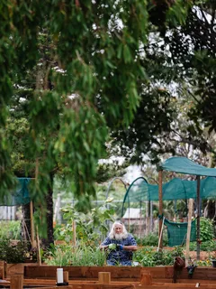 Frau steht im Garten, umgeben von vielen Pflanzen