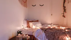 Gemütliches Boho-Zimmer mit Kerzen, Lichterketten und weißem Holzkasten